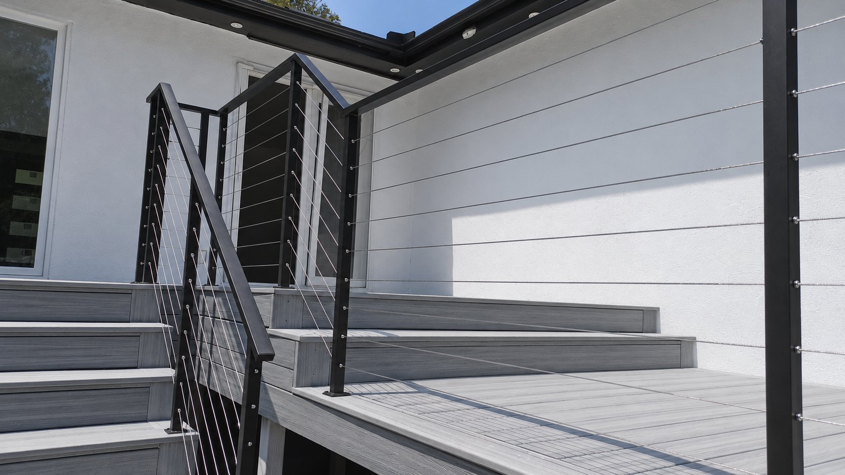 Modern cable railing on composite deck stairs against white siding in Los Angeles