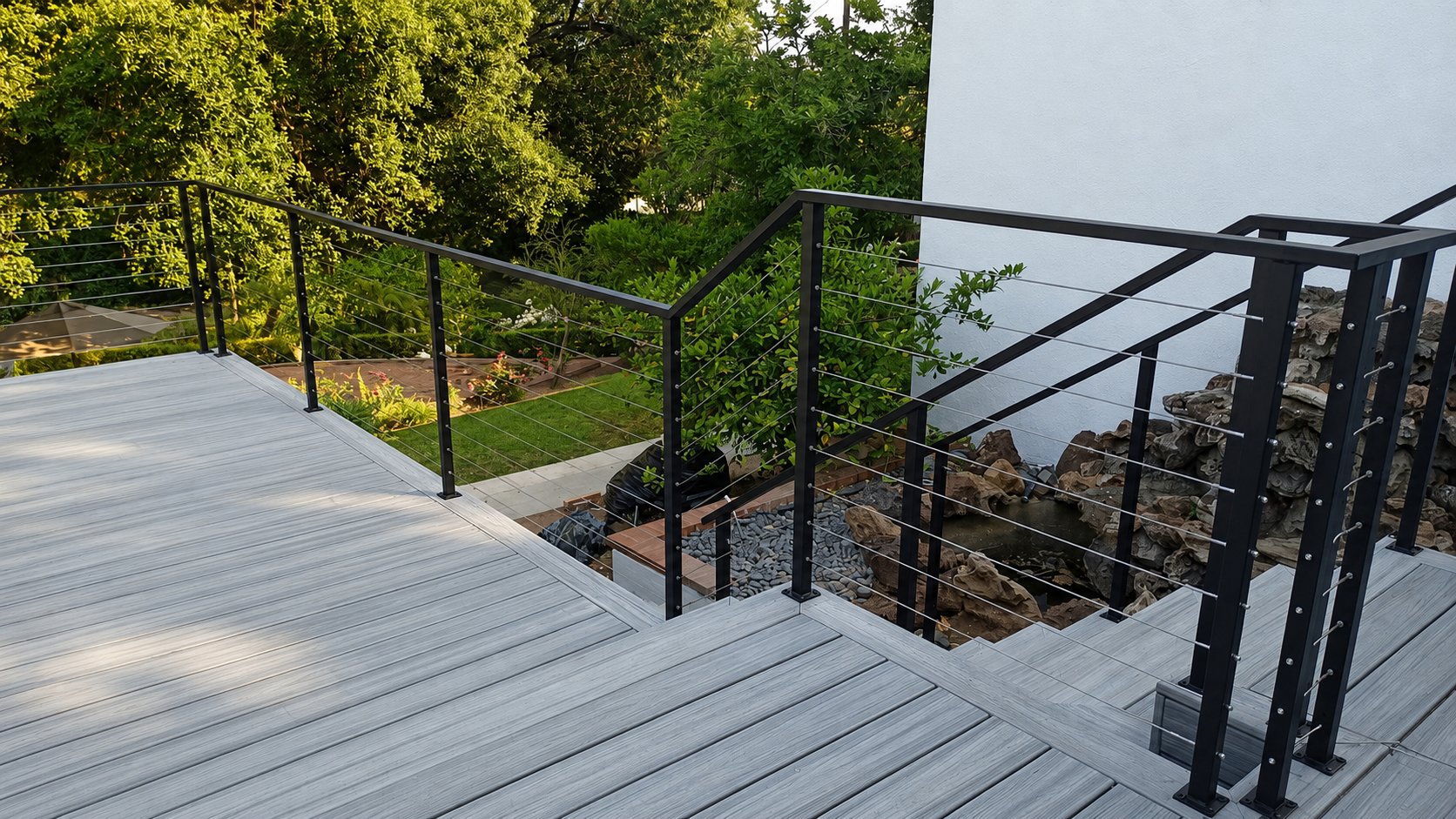 Corner of a composite deck with black-frame stainless cable railing overlooking a yard in Los Angeles