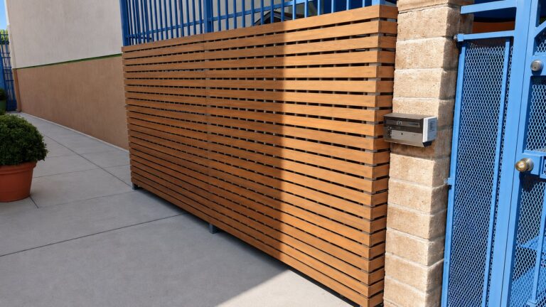 Cedar slat screen integrated with existing blue metal gate and stone column