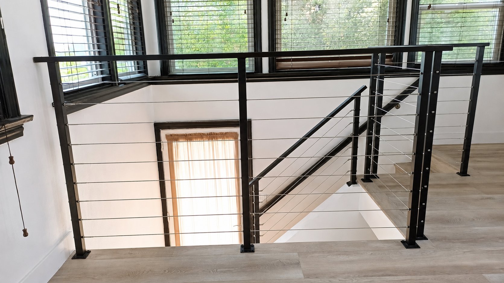 Modern interior cable railing in Los Angeles — black steel posts and top rail around stair opening and loft landing