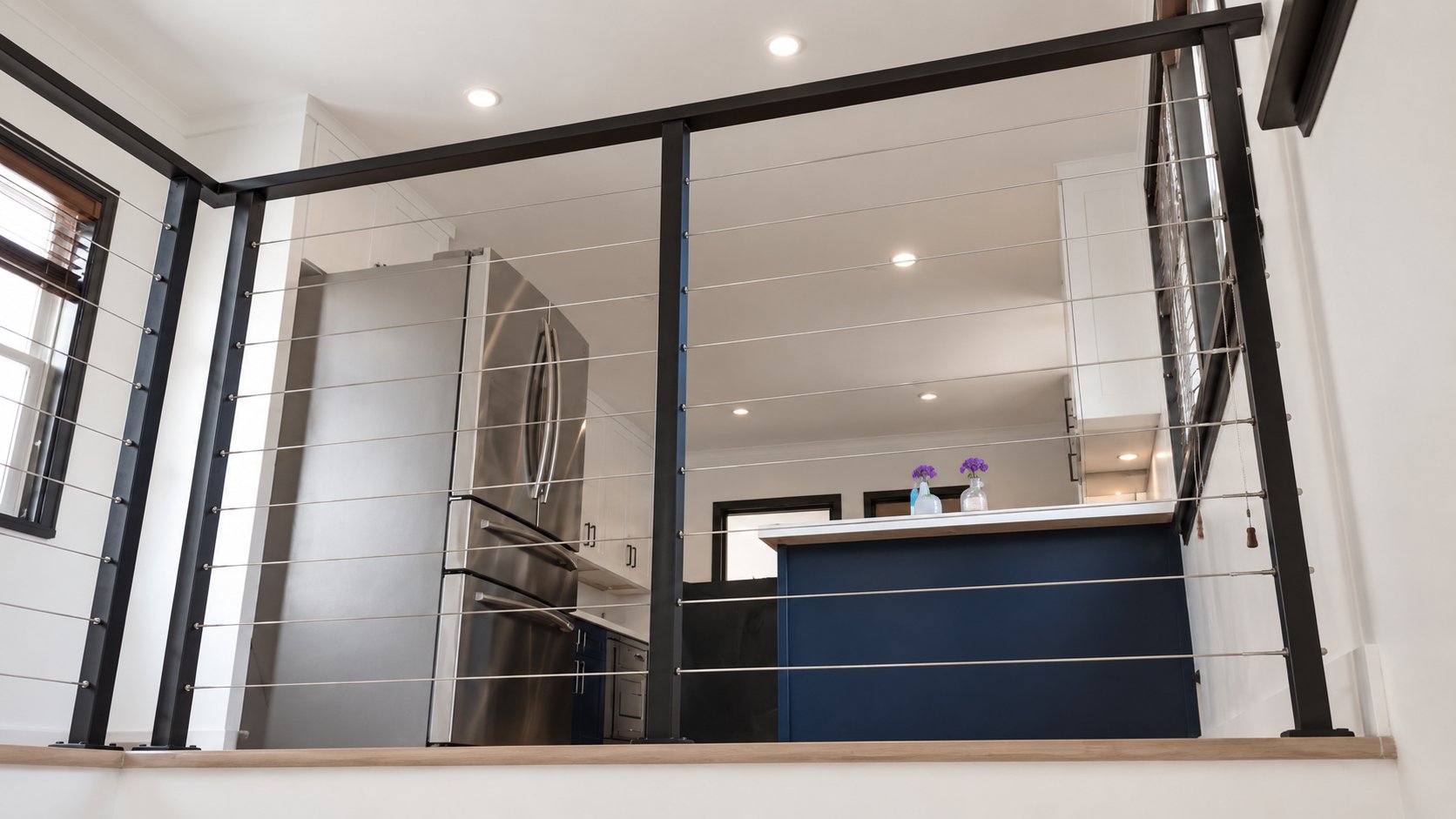 View through interior cable railing toward modern LA kitchen below