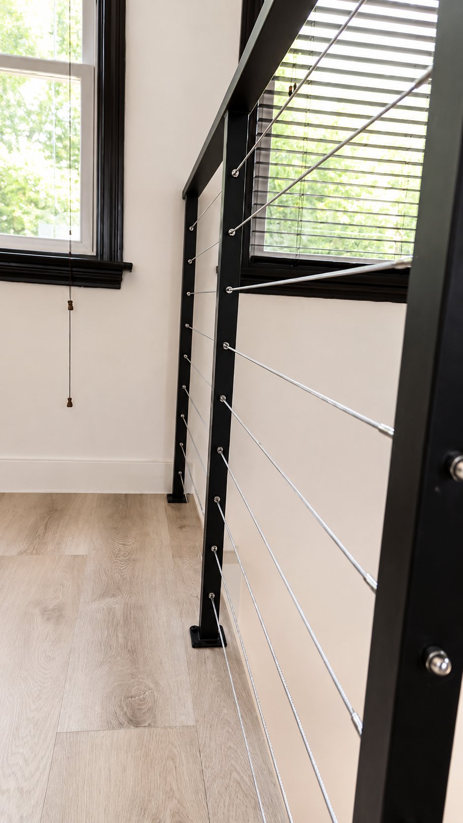 Side view of black steel cable railing along interior staircase in LA
