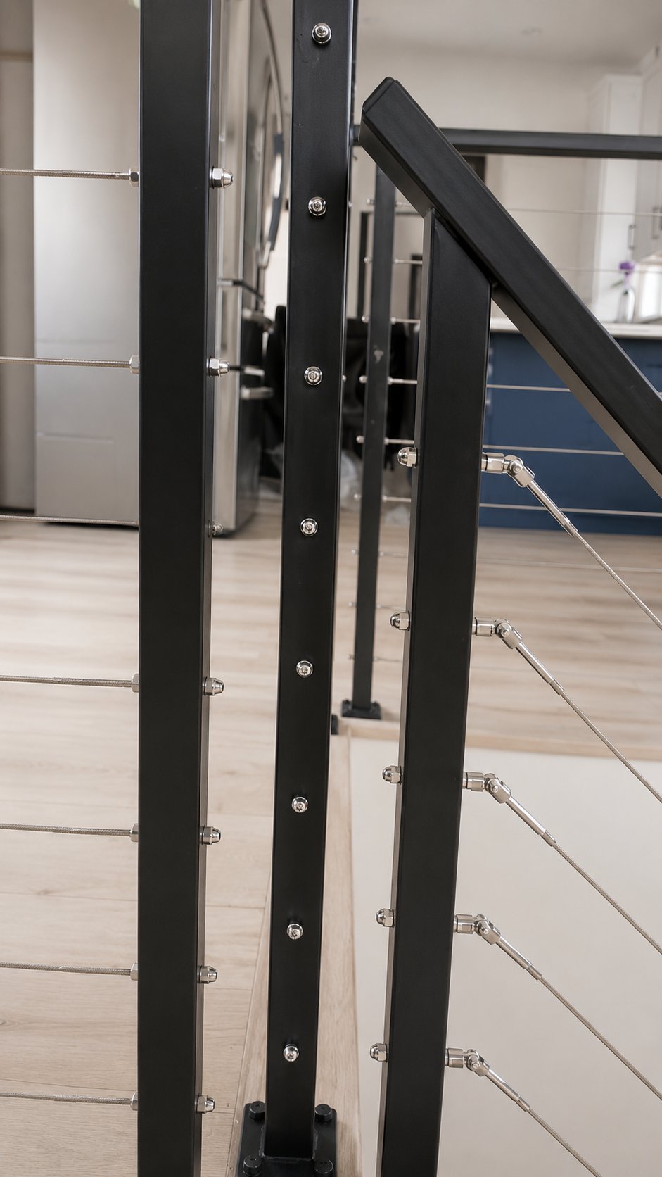 Close-up of black powder-coated steel post with stainless cable infill, interior railing LA