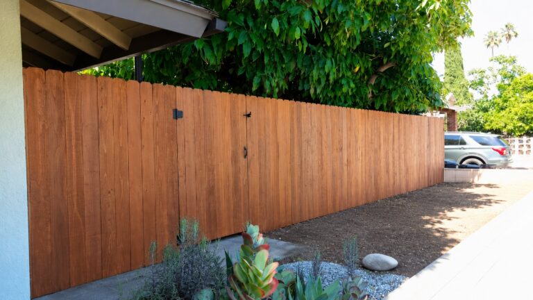 Side-yard cedar gate along stained vertical-board fence run, LA