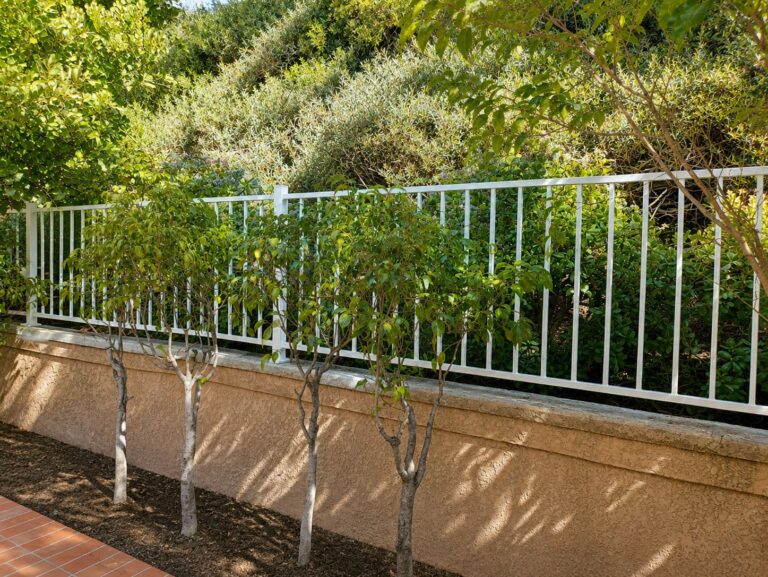 Custom steel picket garden railing on stucco hillside wall — Los Angeles