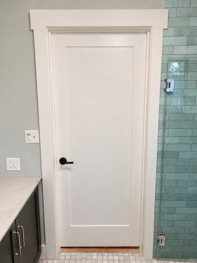 Bathroom doorway with shaker door and custom craftsman header molding — Los Angeles
