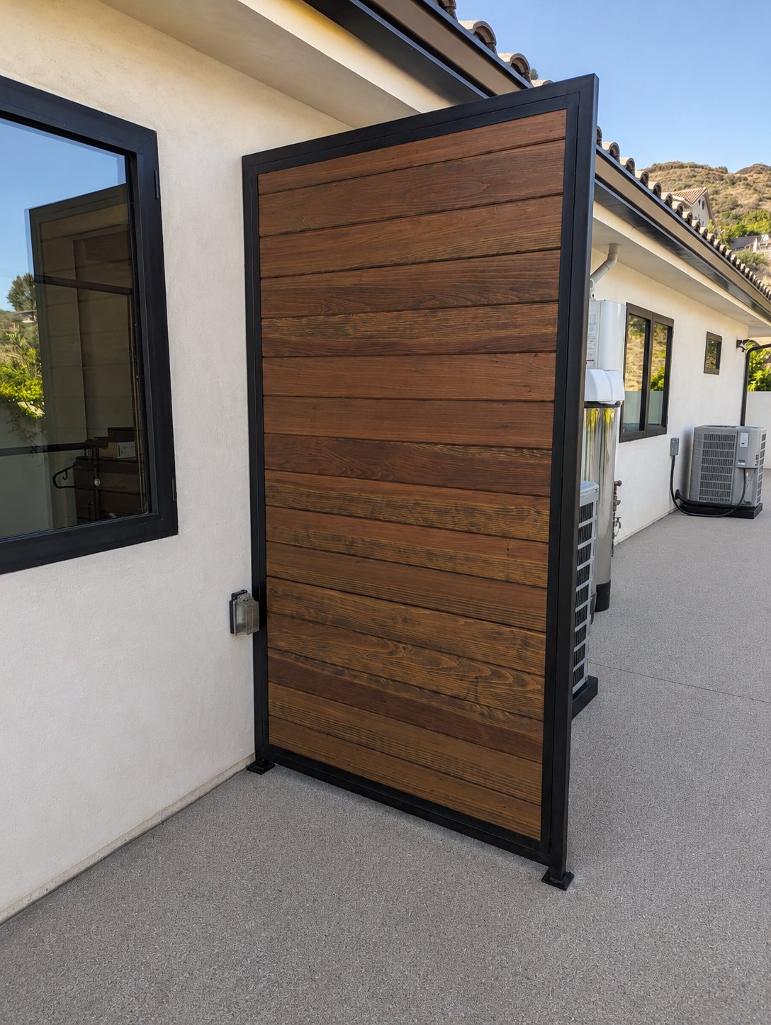 Steel-frame wood utility screen panel concealing exterior access door, premium LA property