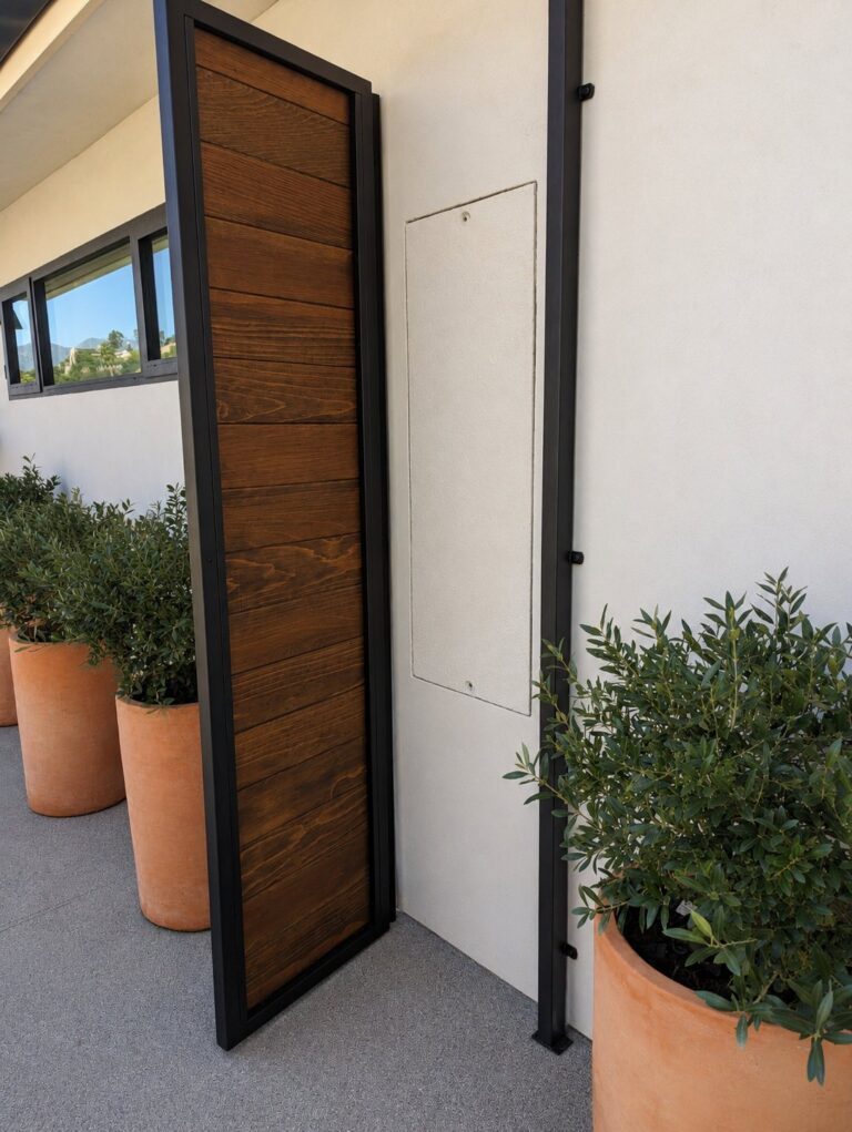 Side angle of steel-frame wood privacy panel with terracotta planters, LA