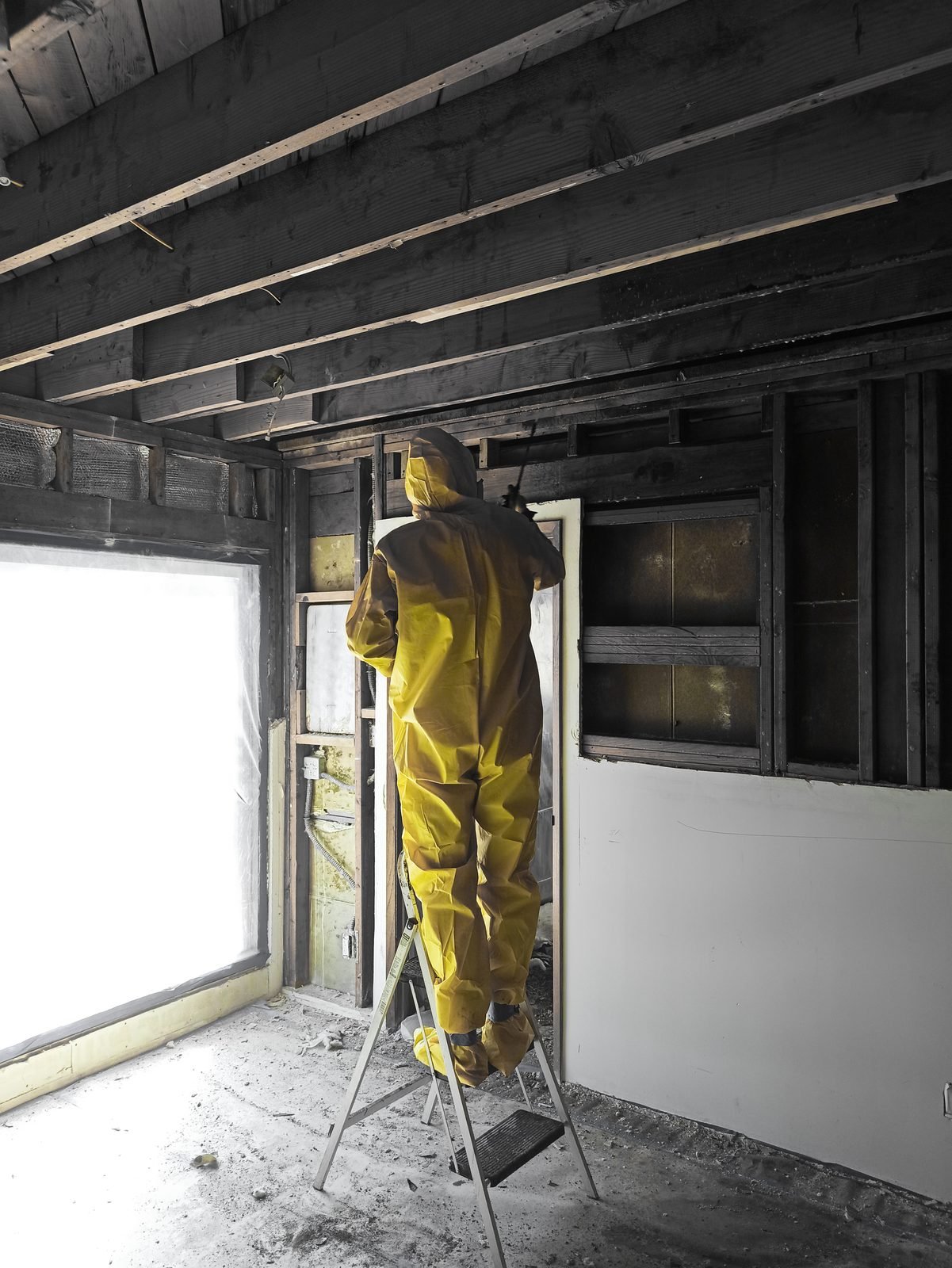 ProHands technician in yellow hazmat suit removing contaminated framing during attic mold remediation in Los Angeles