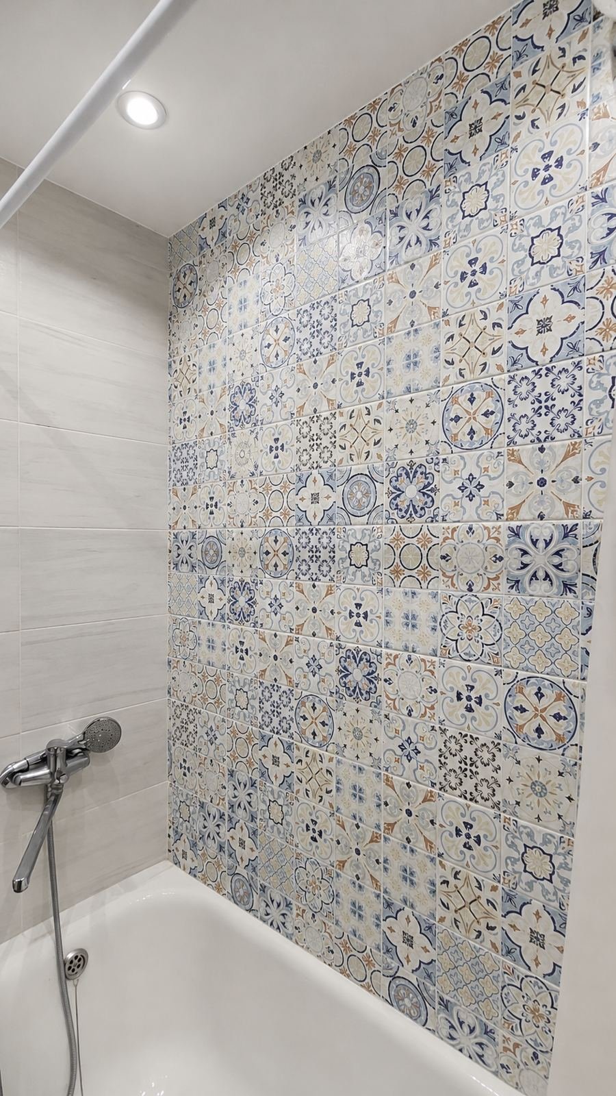 Patterned tile bathroom tub wall with recessed ceiling light and chrome shower fixture — ProHands Los Angeles