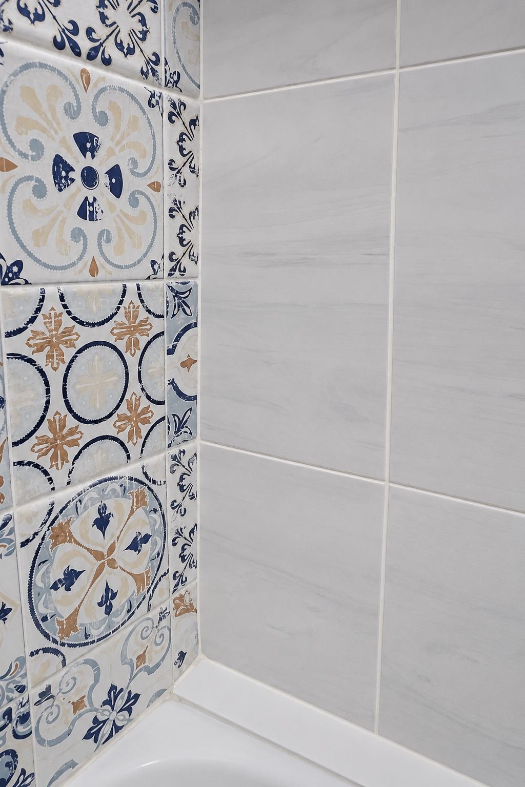 Detail of patterned encaustic tile meeting light gray marble-look tile at bathroom wall corner — ProHands Los Angeles