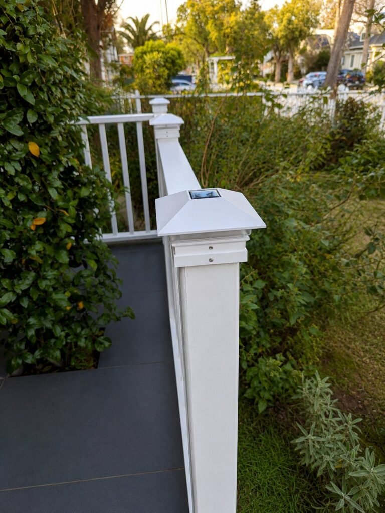 Custom white vinyl porch railing installed by ProHands in Los Angeles, close-up of pyramid post cap with solar light