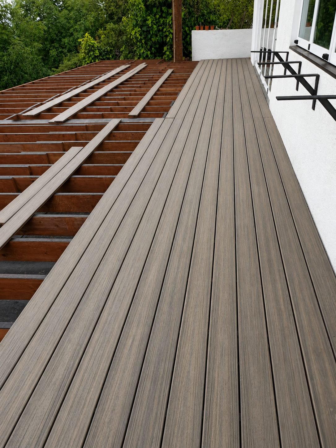 Cable railing close-up — stainless cable tensioners in black steel posts on composite deck — ProHands Los Angeles