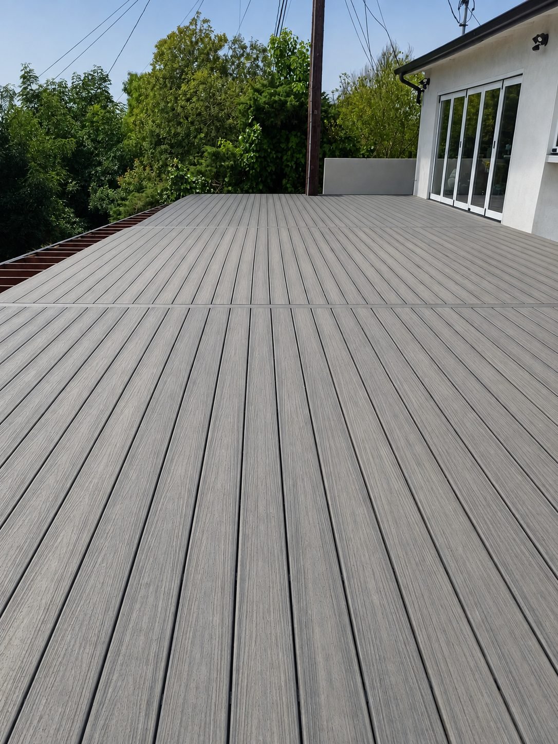 Composite deck installation in Los Angeles — open expanse of grey composite boards leading to modern white house — ProHands Home Improvement