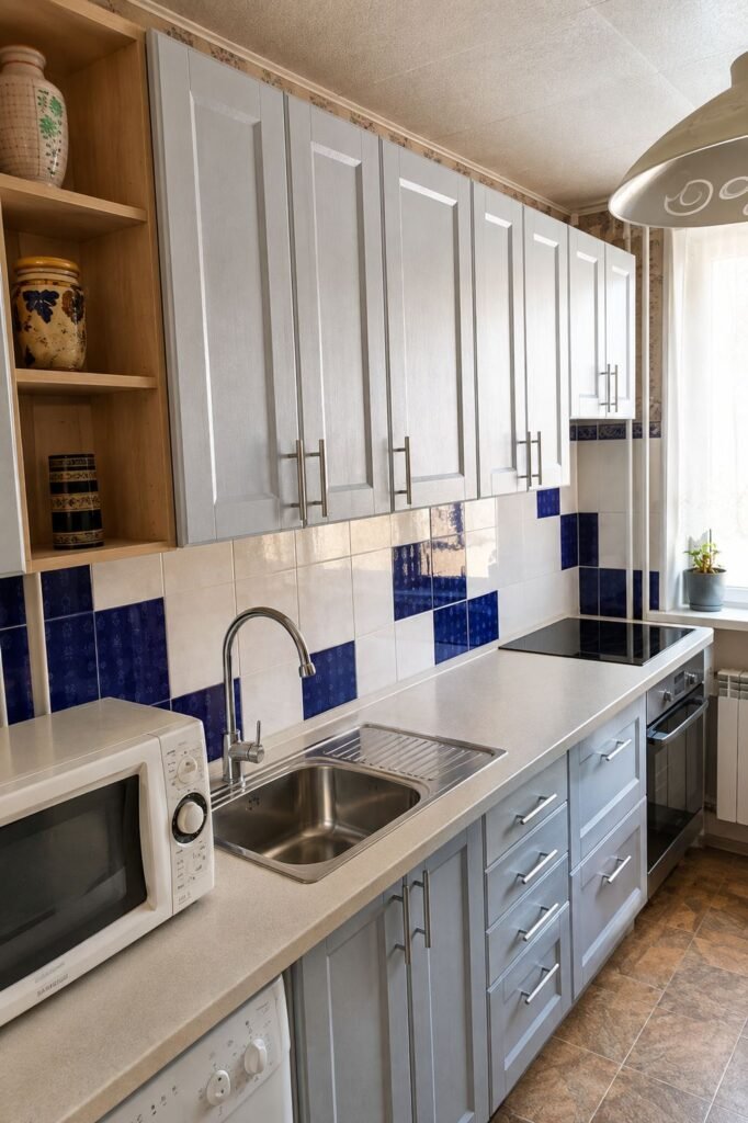 Custom compact galley kitchen with light gray shaker cabinets, blue-and-cream tile backsplash, brushed steel pulls and cream quartz counter — ProHands Los Angeles