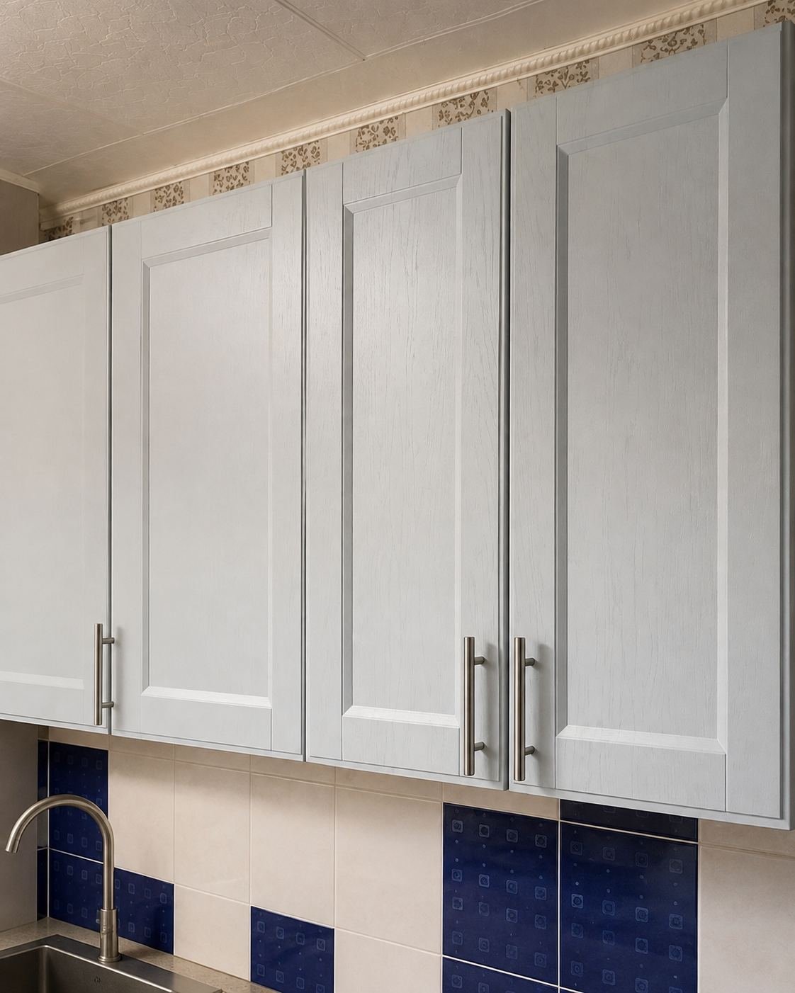 Close-up of custom light gray shaker cabinet doors with visible wood grain and brushed steel bar pull — ProHands Los Angeles kitchen