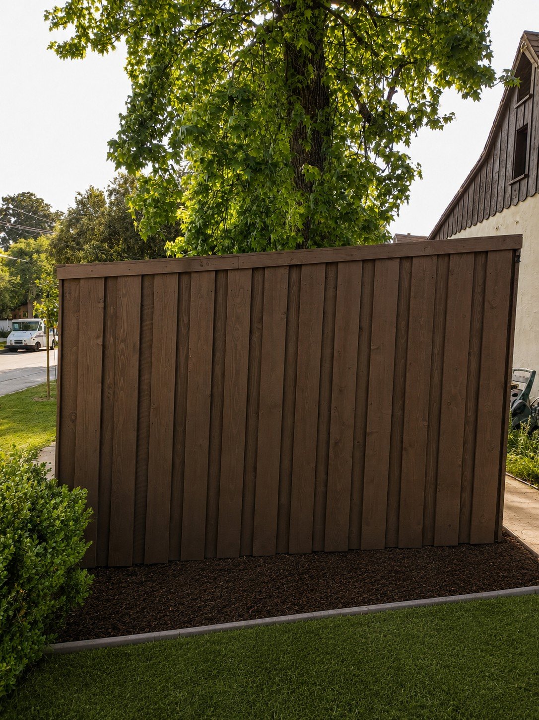 Espresso board-and-batten fence single panel — wide boards with narrow batten strips, cap rail on top, maple tree overhead — ProHands Los Angeles