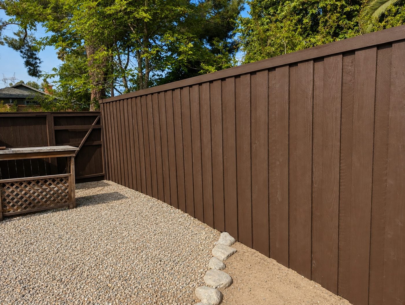 New board-and-batten cedar fence corner in Los Angeles backyard with pea gravel and cobblestone edging — chocolate brown stain finish — ProHands Home Improvement