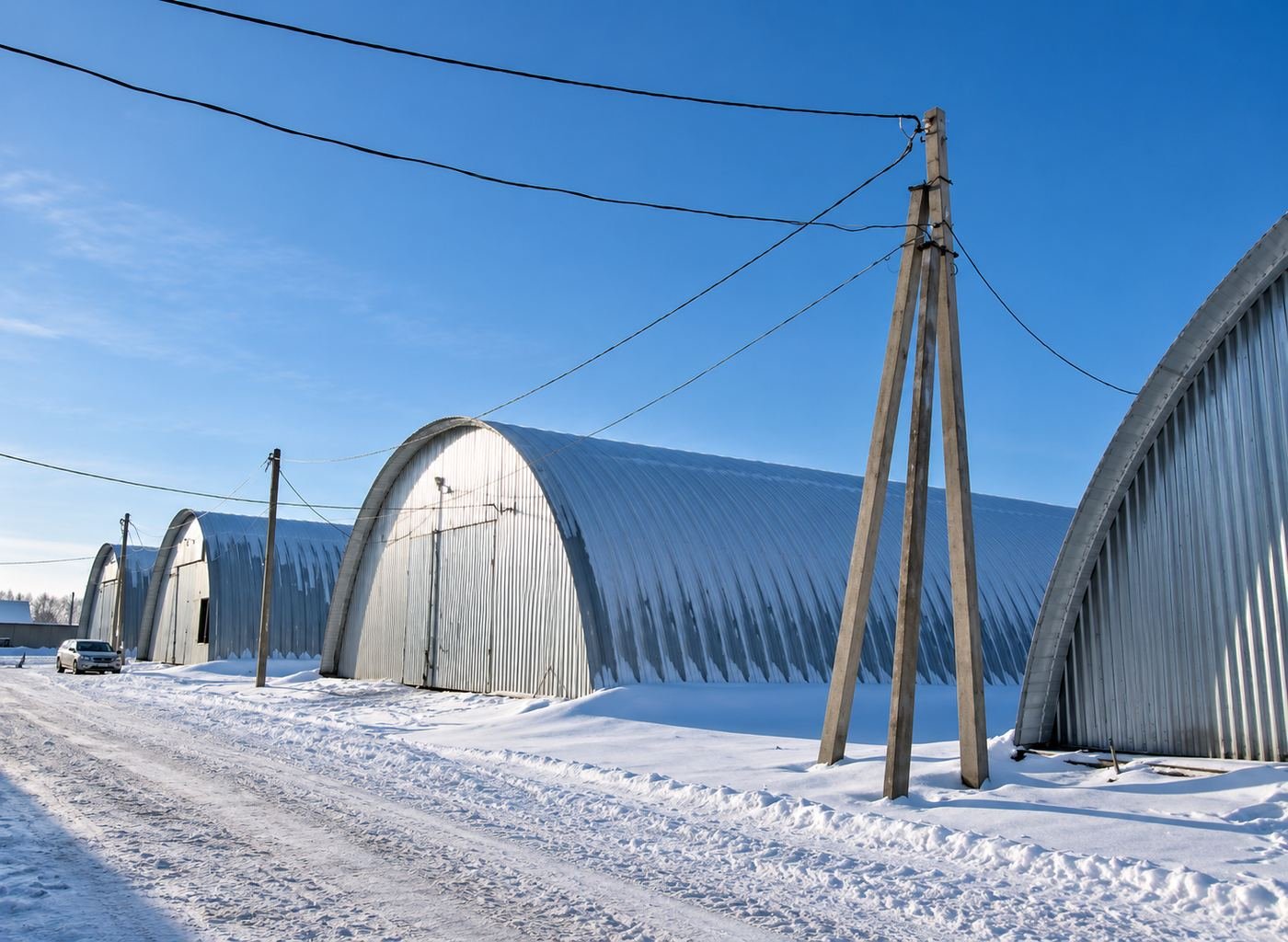 Row of steel-arch grain-storage hangars we built in Russia, photographed in winter with fresh snow and clear blue sky