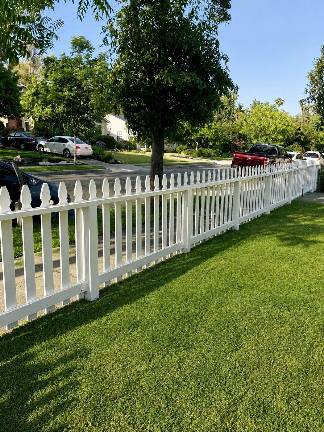 Classic white picket fence with pointed scalloped-top pickets along a lush lawn fronting a tree-lined residential street in San Marino, Los Angeles — ProHands