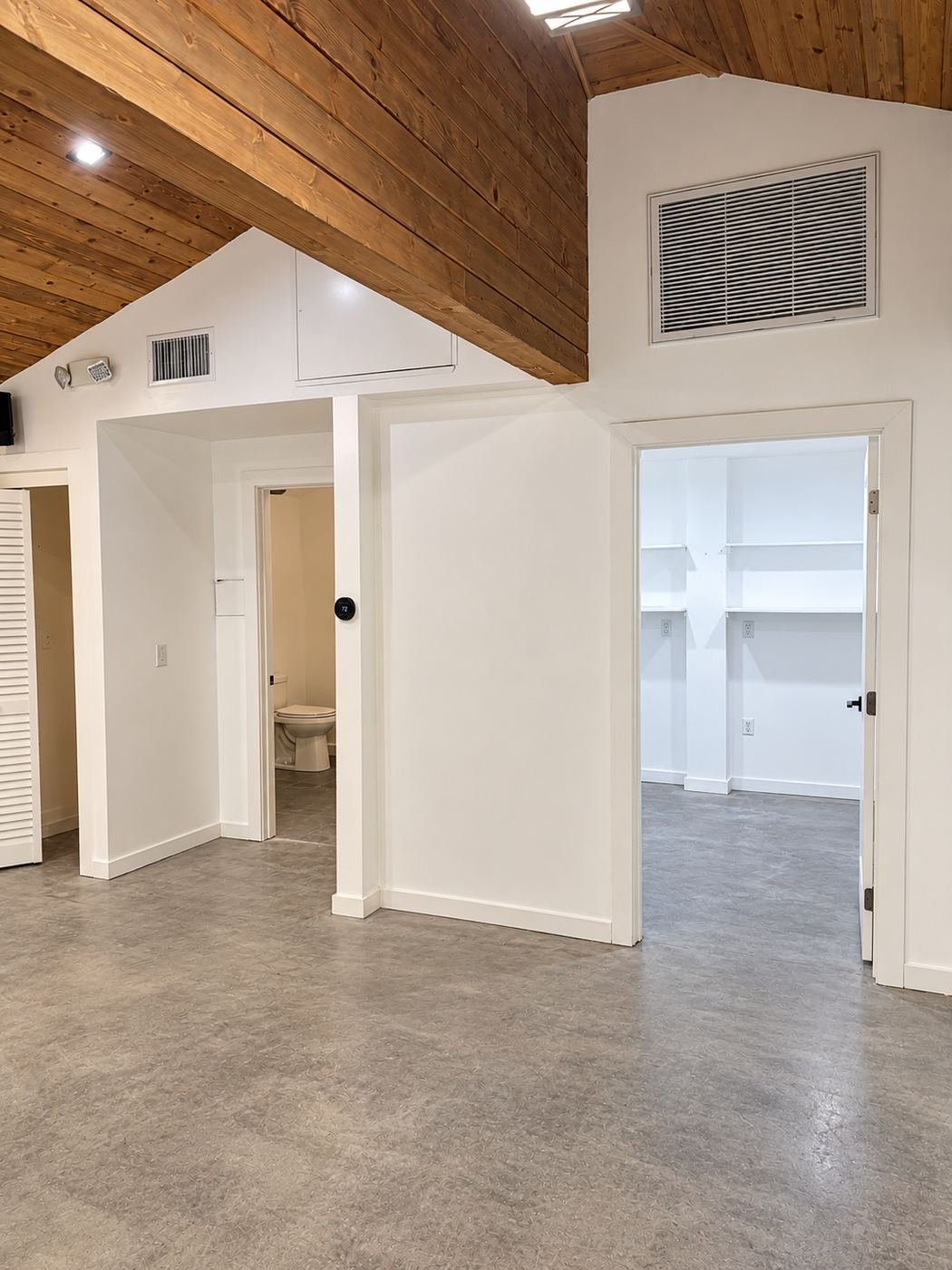 New interior partitions inside the showroom — restroom, storage room and closet carved out of the open shell with white shaker-style doors and finished concrete floor — ProHands Los Angeles commercial buildout