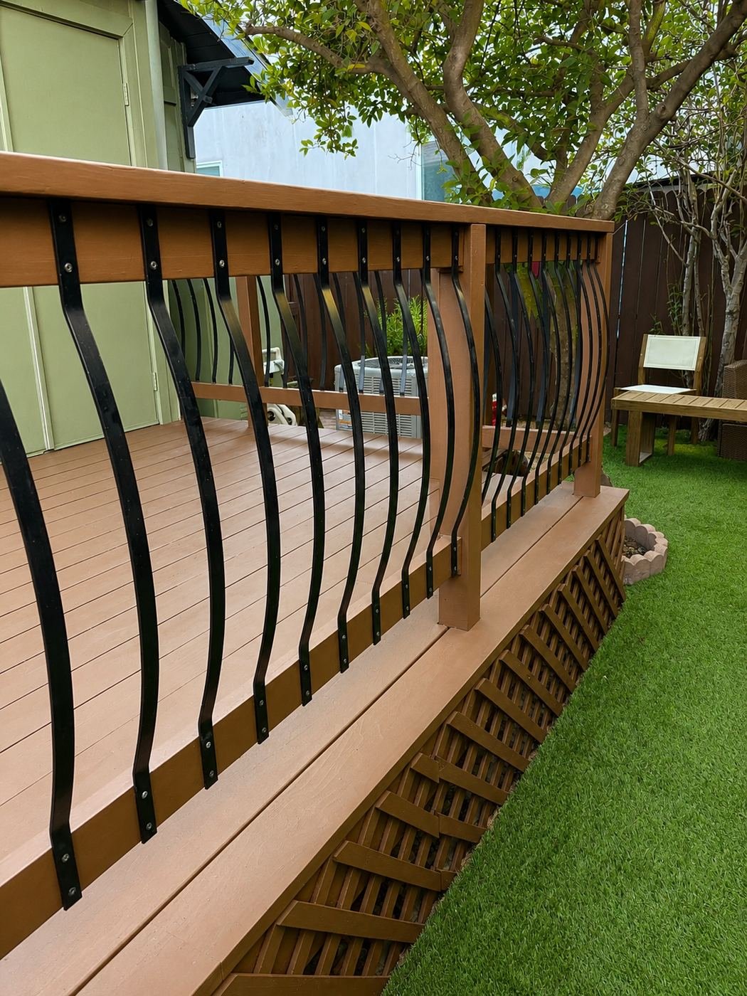 Restored wood deck railing with decorative bowed black metal balusters and freshly repainted warm brown top rail and posts — ProHands Los Angeles
