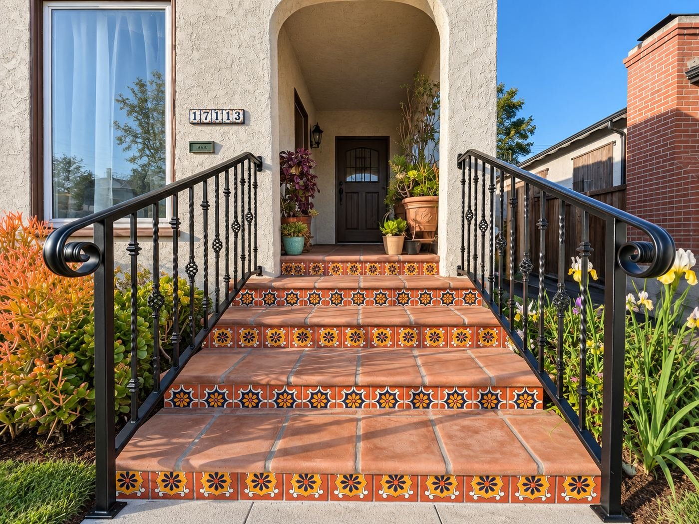 Symmetric front view of custom wrought-iron handrails on both sides of saltillo-tile Spanish steps with painted Talavera-tile risers at a classic Los Angeles stucco home — ProHands