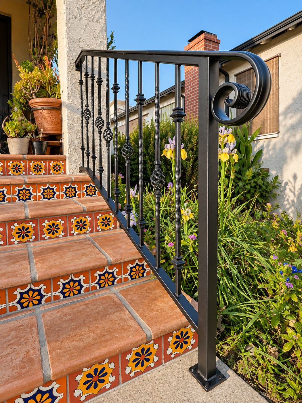 Right-side custom wrought-iron handrail with decorative basket spirals, next to iris flowers in bloom — ProHands wrought-iron fabrication, Los Angeles