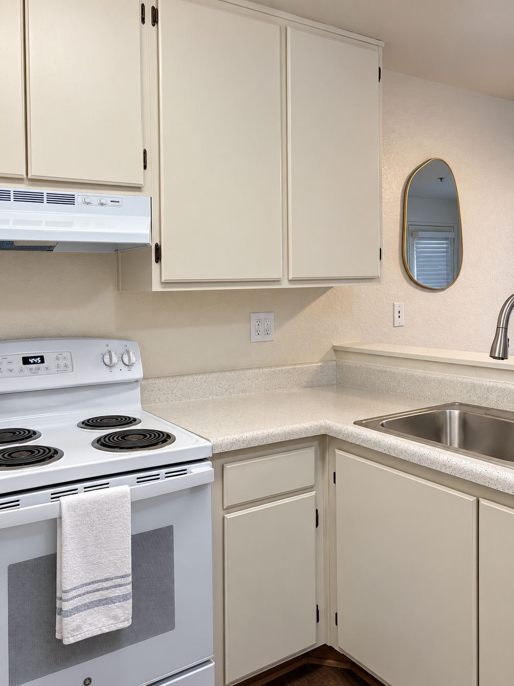 Freshly painted warm-white kitchen cabinets at a Glendale apartment, with new black-and-brass pulls — ProHands cabinet refinish