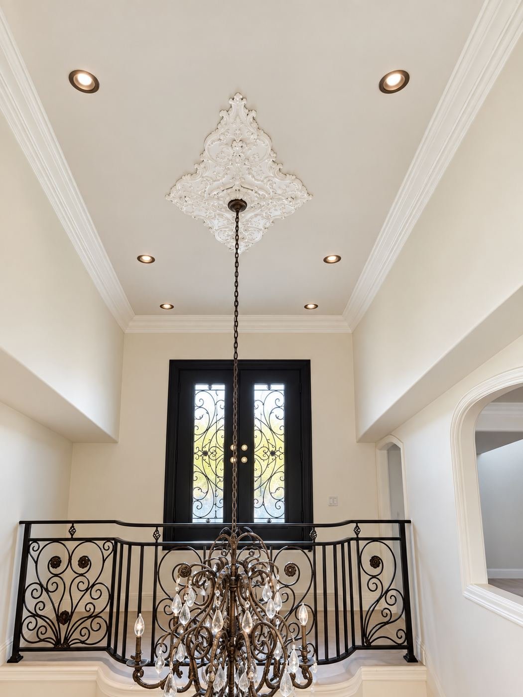 Interior remodeling in Los Angeles — grand two-story foyer of a Mediterranean mansion remodel with iron entry doors and chandelier