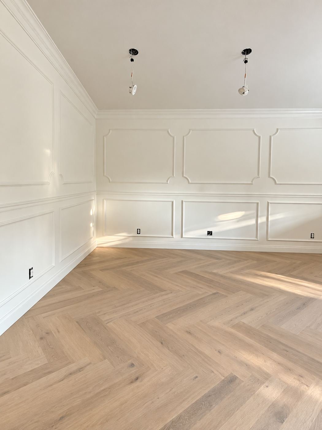 Corner of a formal room with raised-panel wainscot and light-oak herringbone floor — Mediterranean mansion remodel, Los Angeles