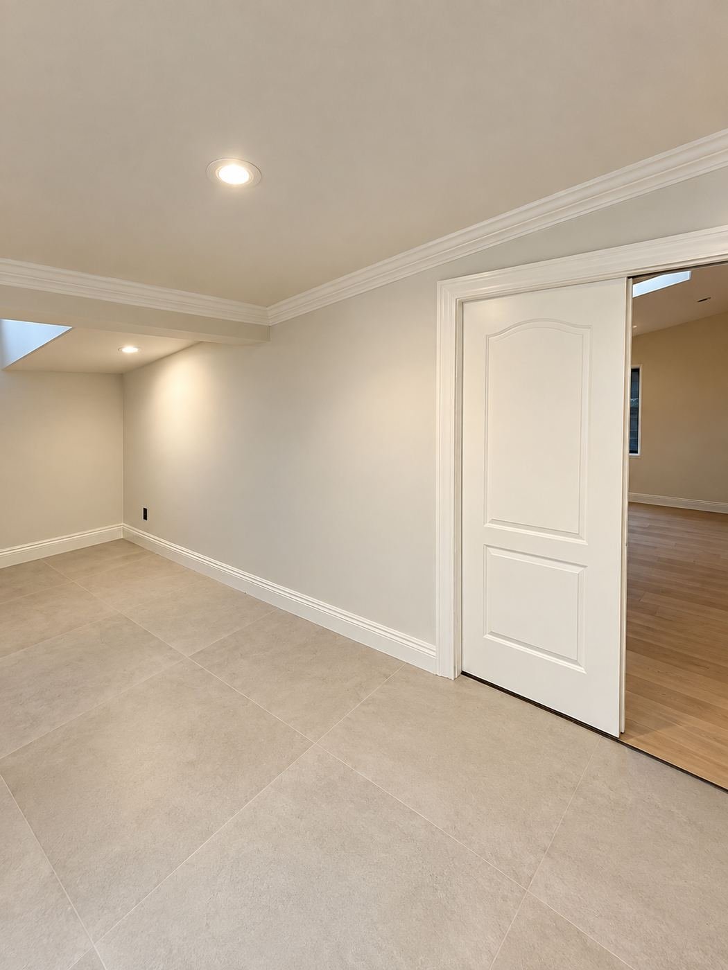 Finished transitional hallway with a wall opening to the next room, warm cream paint and large-format tile floor — Mediterranean mansion remodel, Los Angeles