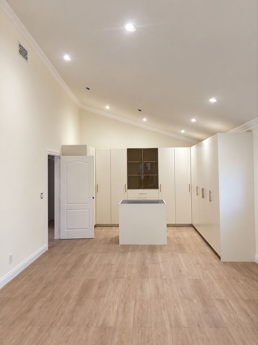 Vaulted-ceiling room with light-oak floor, central island and a long wall of built-in closets — Mediterranean mansion remodel, Los Angeles
