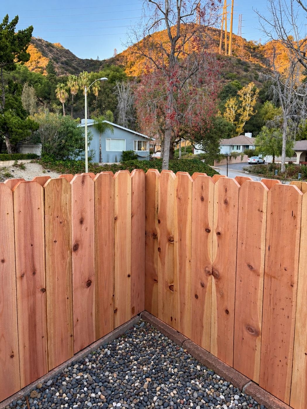 Dog-ear corner of a natural cedar privacy fence at sunset with Glendale foothills in the background — ProHands Los Angeles