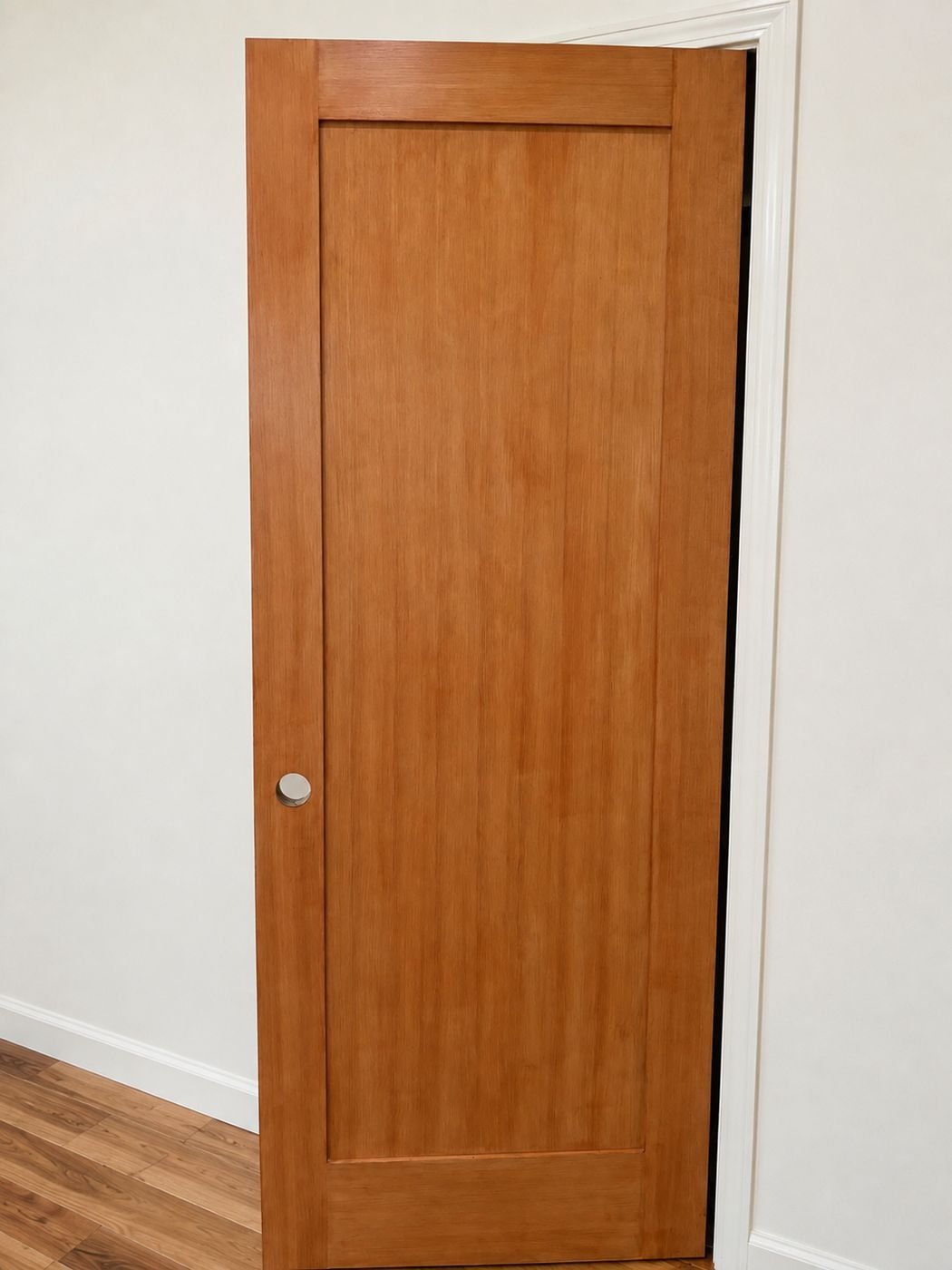 Solid wood single-panel Shaker interior door hung and stained in warm honey tone, white walls and hardwood floor — ProHands Los Angeles