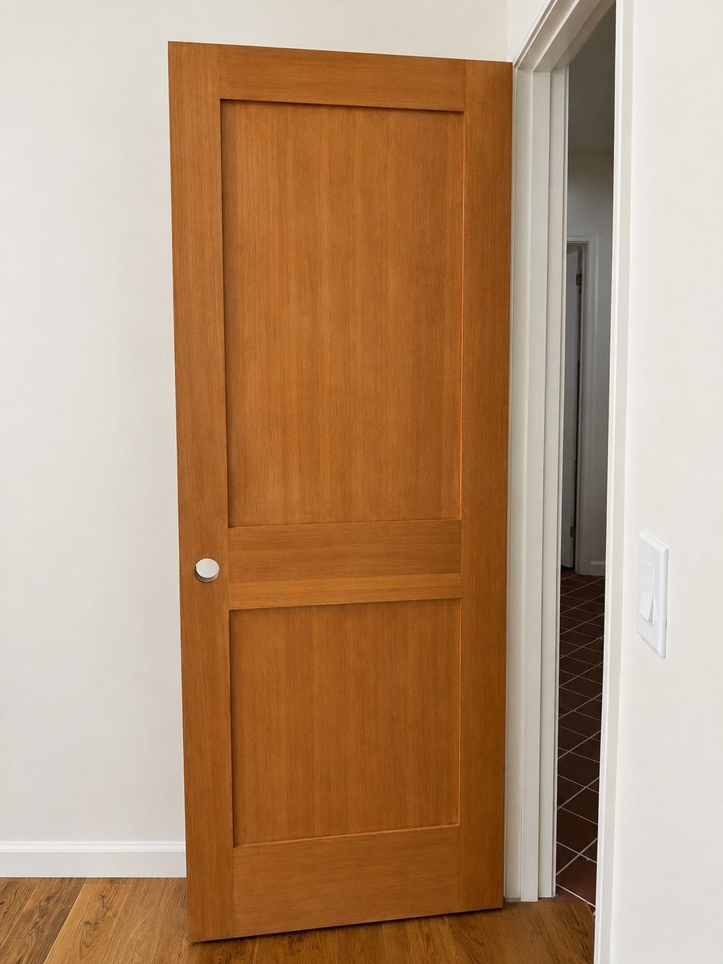 Solid wood two-panel Shaker interior door with amber stain finish between living area and hallway with hardwood floor — ProHands Los Angeles