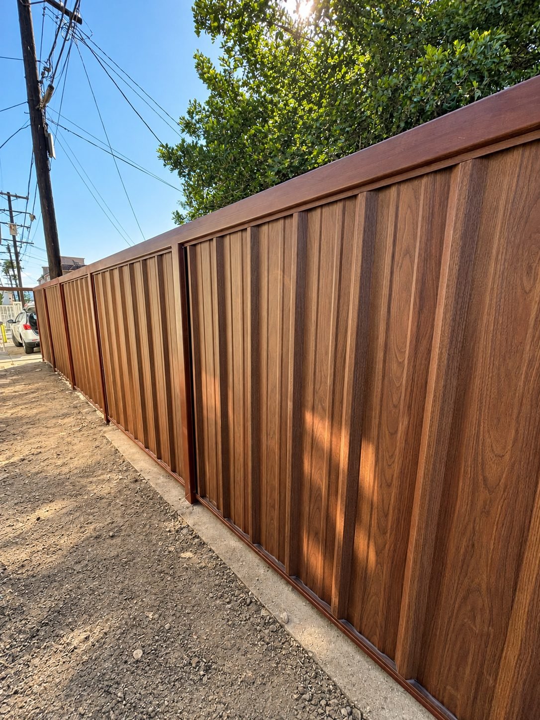 Finished wood-grain look steel fence with rich natural wood tone panels — ProHands Los Angeles