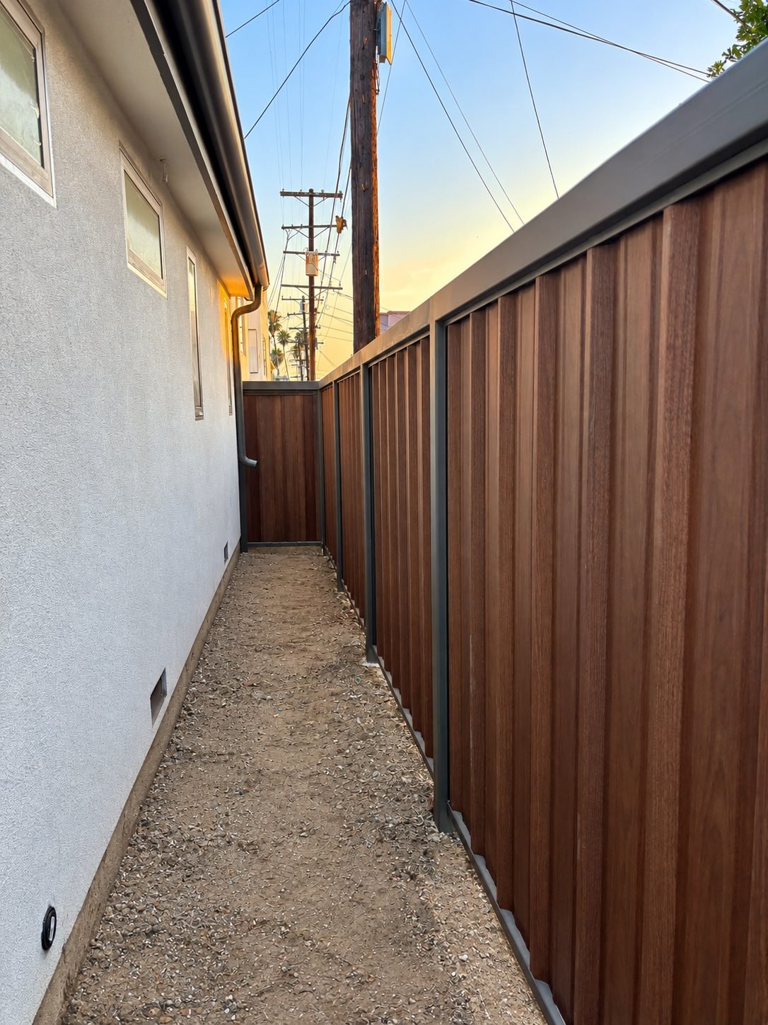 Sunset view down a side yard with wood-grain steel fencing in rich brown