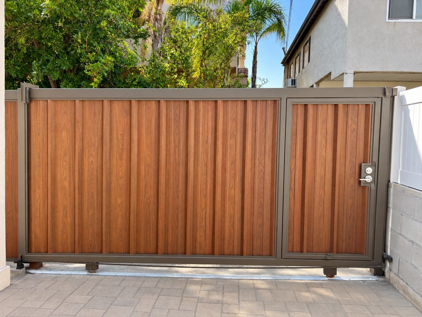 Electric sliding gate with built-in pedestrian door in wood-grain finish
