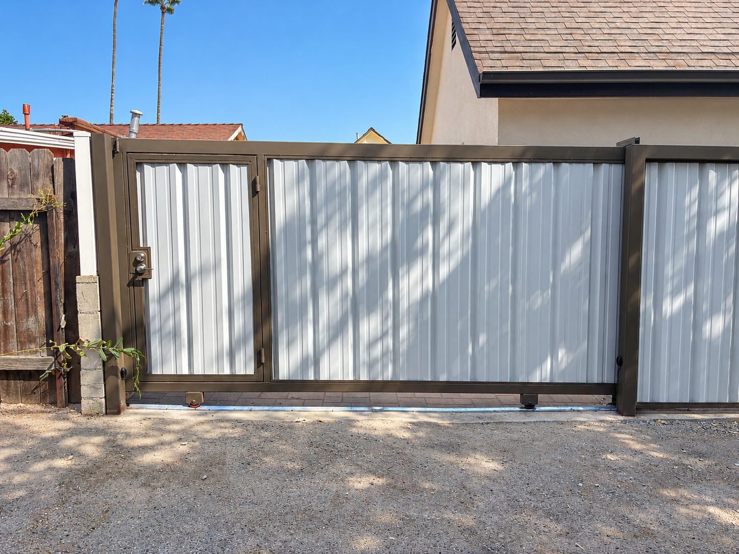 Side view of electric sliding gate with track and roller mechanism, pedestrian door built in