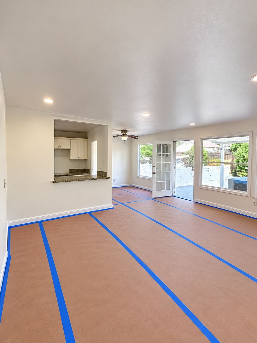 Full room masking before interior repaint — the client's laminate floor fully covered edge-to-edge with red rosin paper and sealed to the baseboards with blue painter's tape, Van Nuys water-damage restoration — ProHands