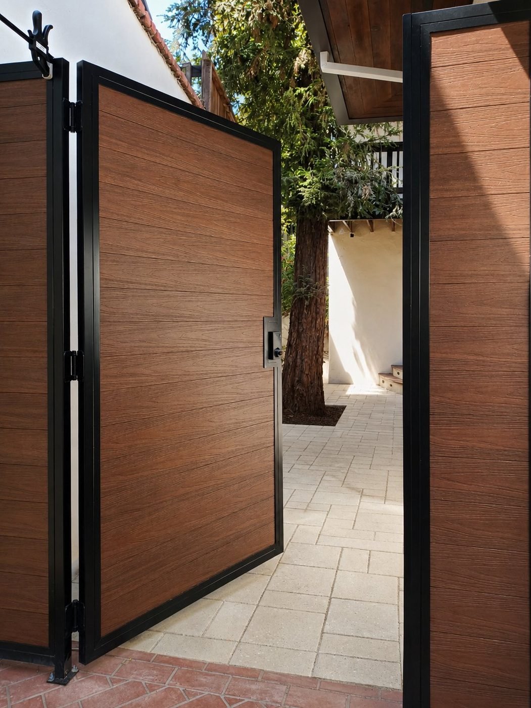 Composite and steel pedestrian gate open from courtyard side showing walnut-tone composite panels and black steel frame - ProHands